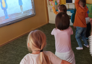 Dzieci tańczą przed tablicą multimedialną